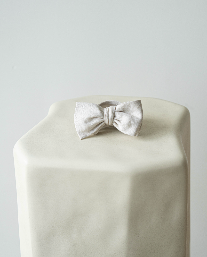 White bow tie on a white pedestal against a light gray background