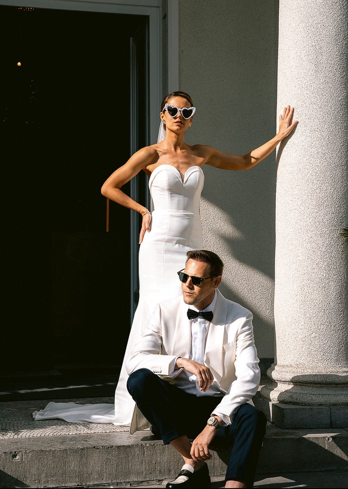 Man and woman in formal attire standing on steps with a columned building in the background