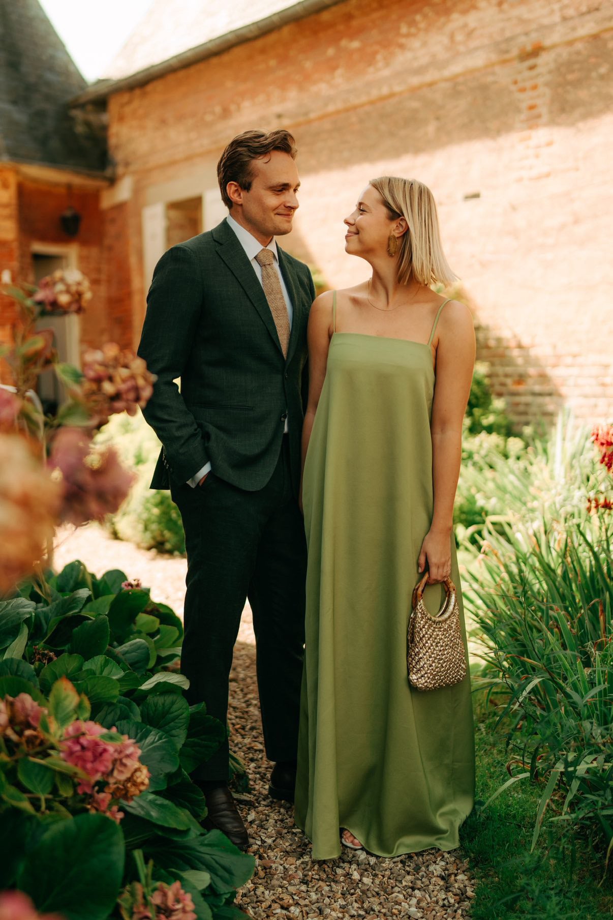 Man in groen maatpak en vrouw in groene jurk poserend in een tuin