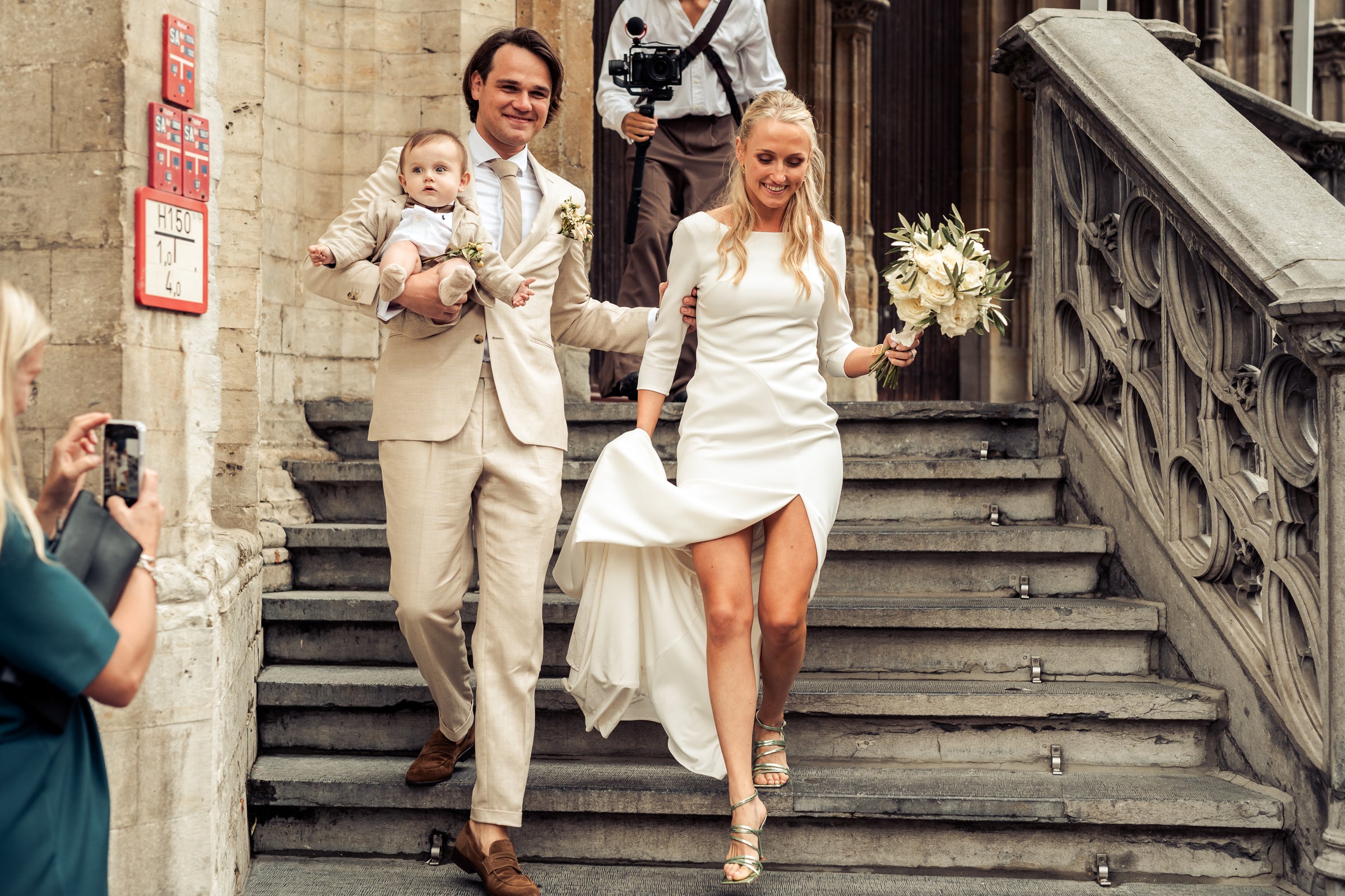 Wedding couple with a baby walking down steps outside a building