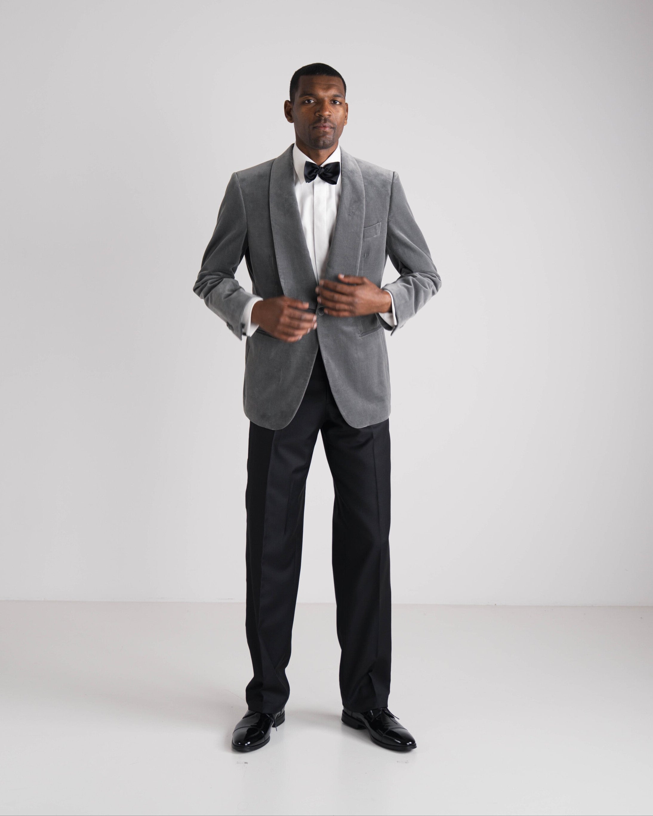 man in grijze velvet diner jacket en zwarte broek en strik