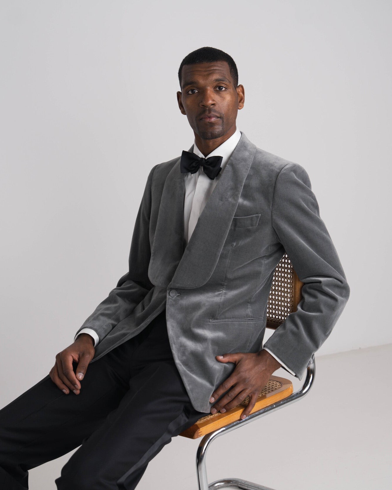 man in grijze velvet diner jacket en zwarte broek en strik