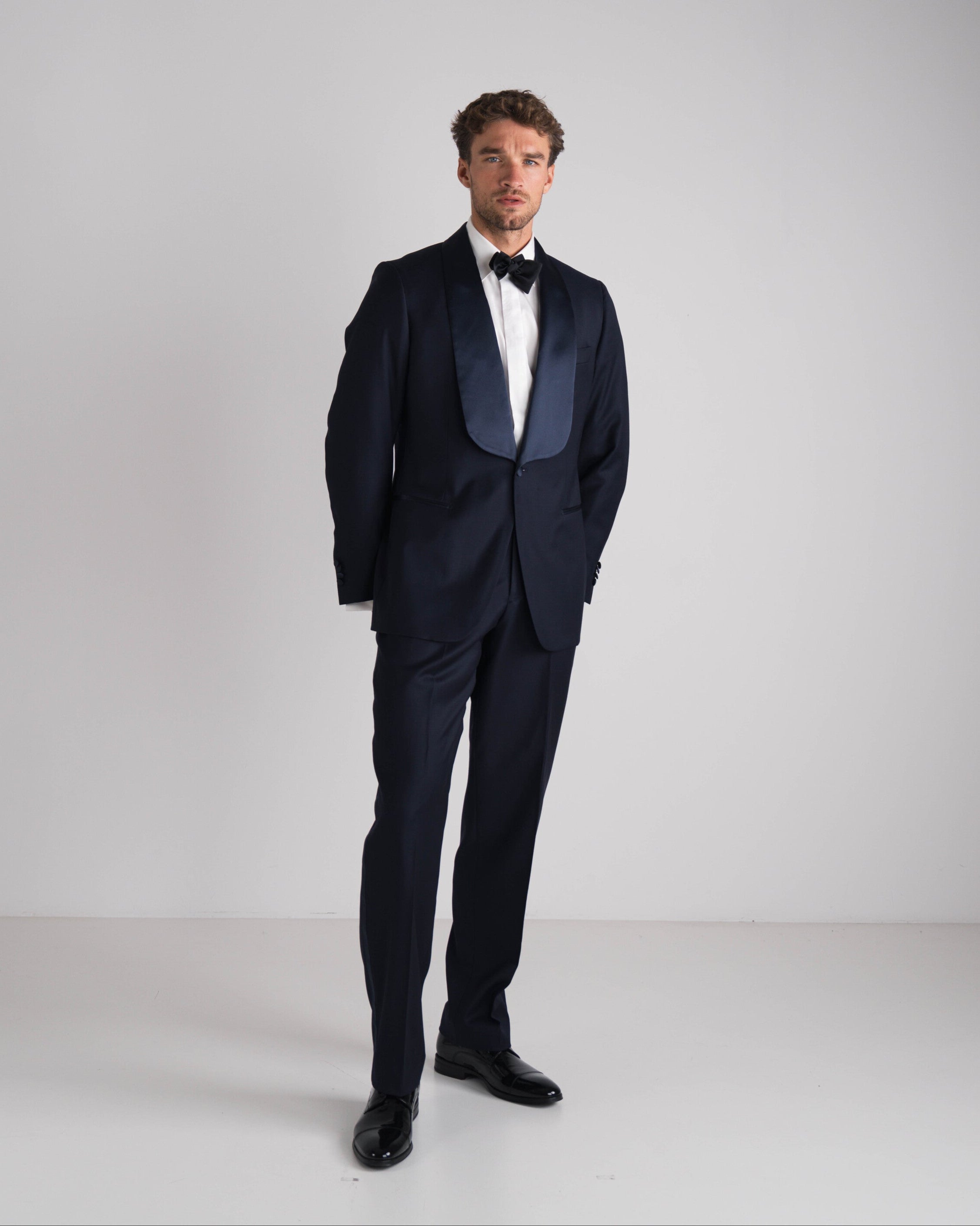 staande man in blauwe tuxedo met zwarte strik