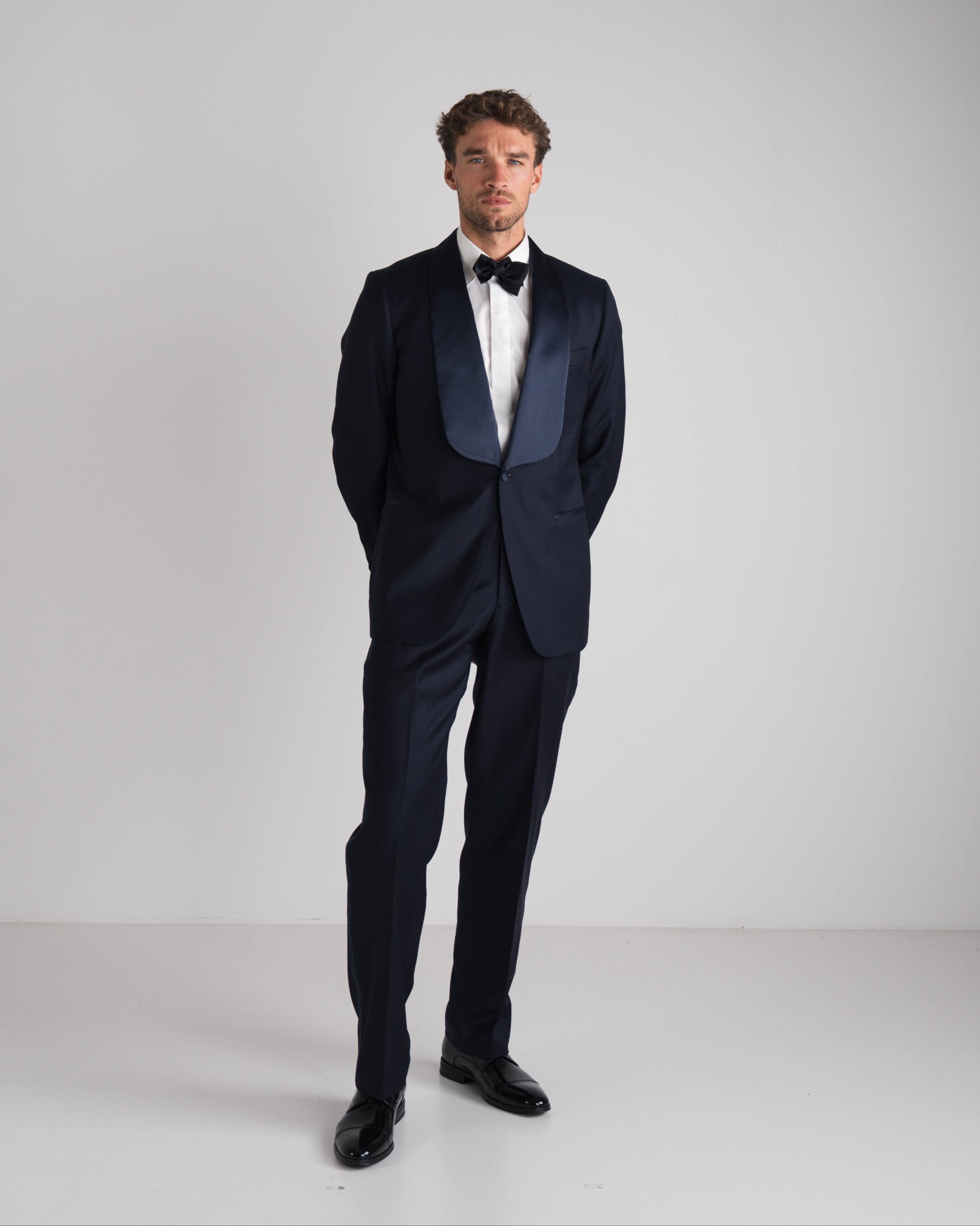 staande man in blauwe  tuxedo en zwarte strik