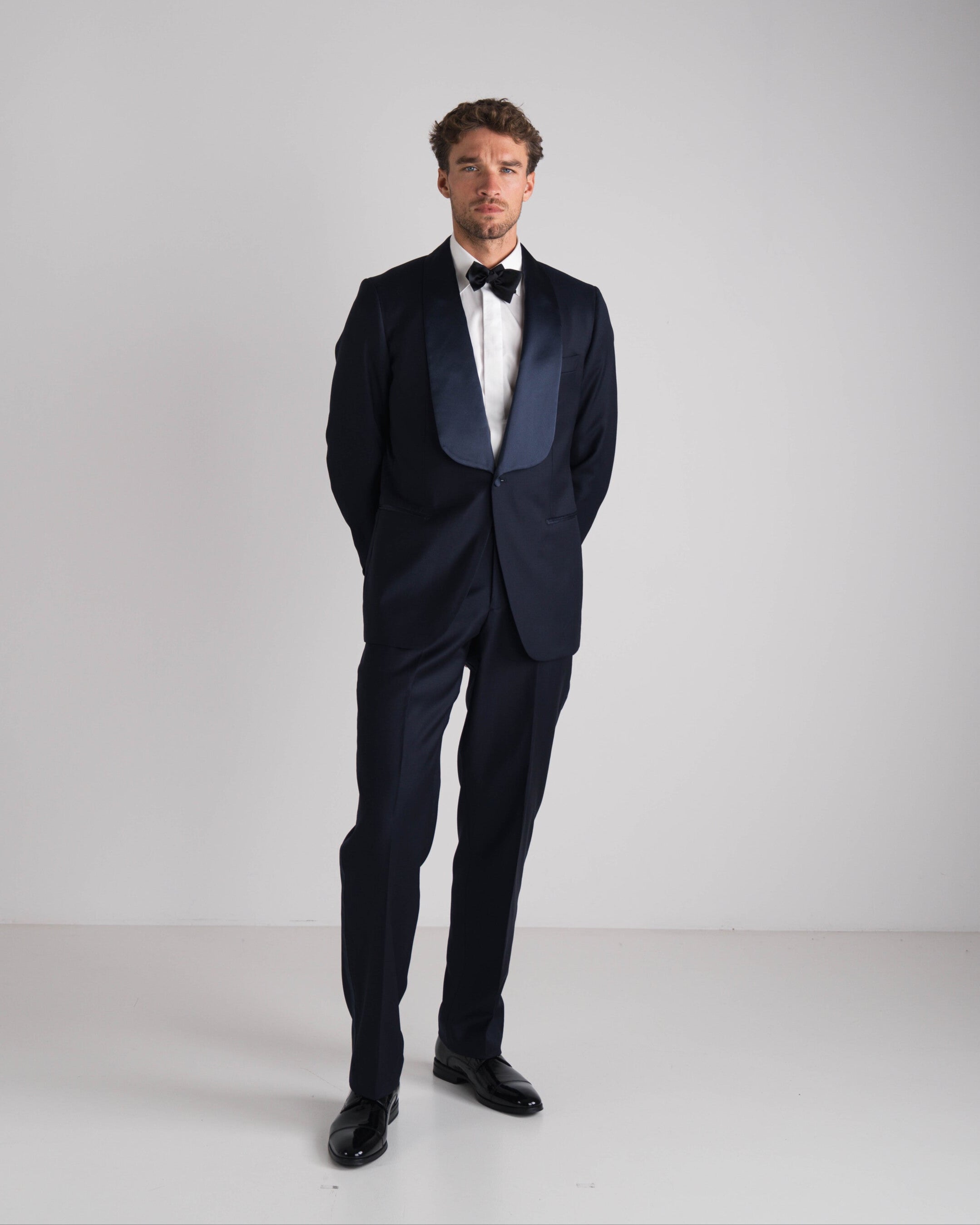 staande man in blauwe tuxedo met zwarte strik