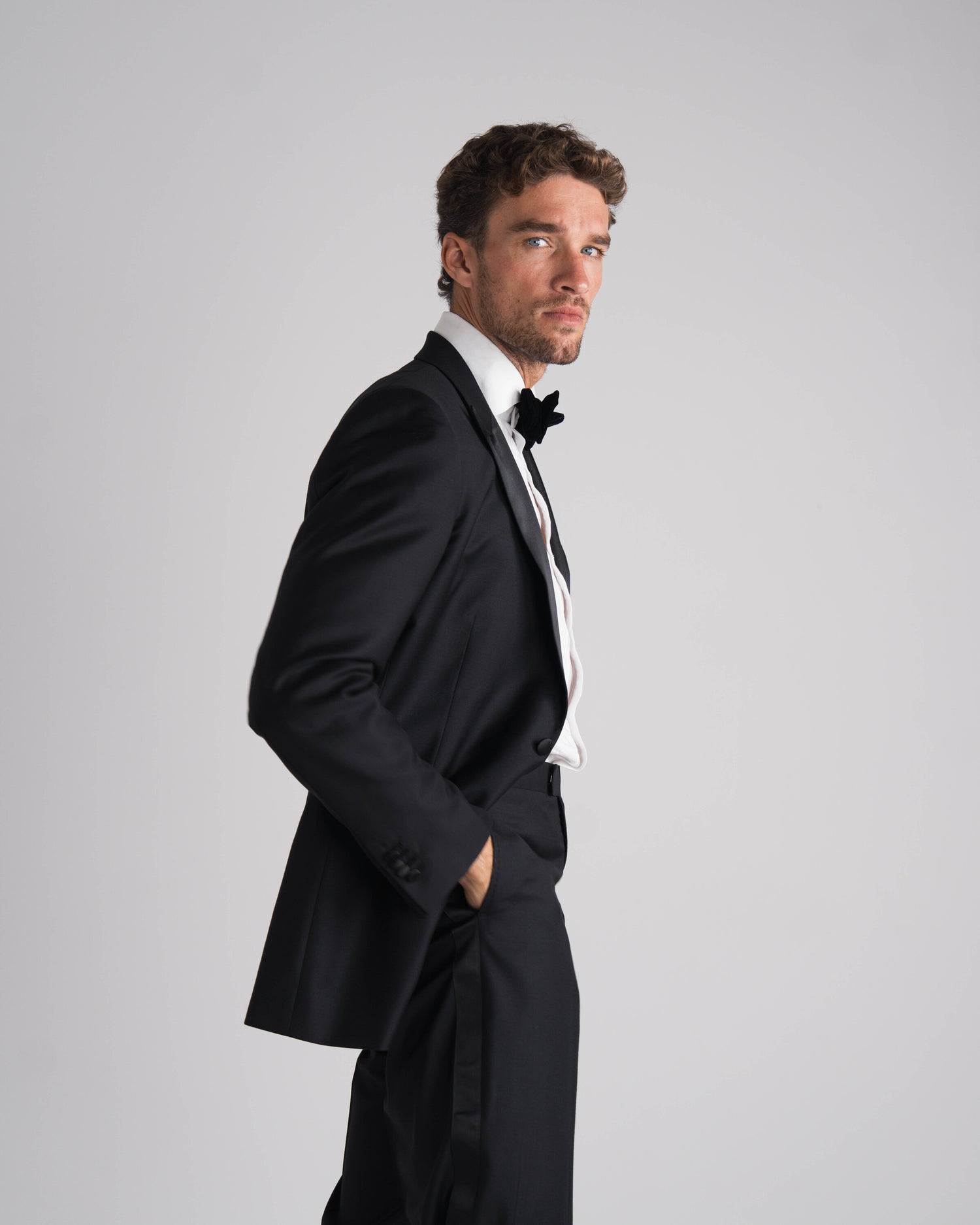 staande man in zwarte tuxedo half gedraaid en zwarte strik 