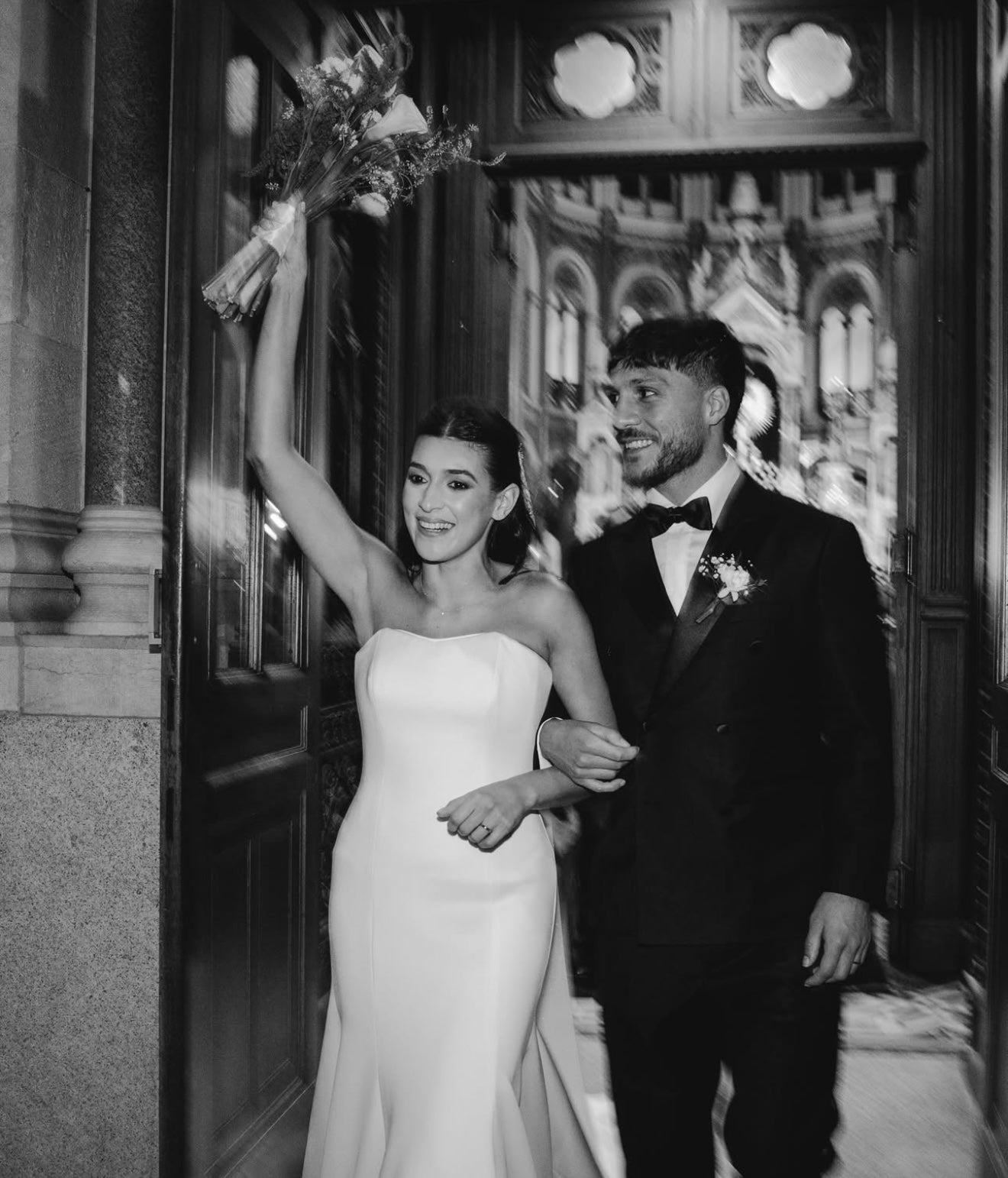 Black and white photo of a bride and groom, Kevin Mac Allister, footballplayer of Union, standing in front of an ornate door.
