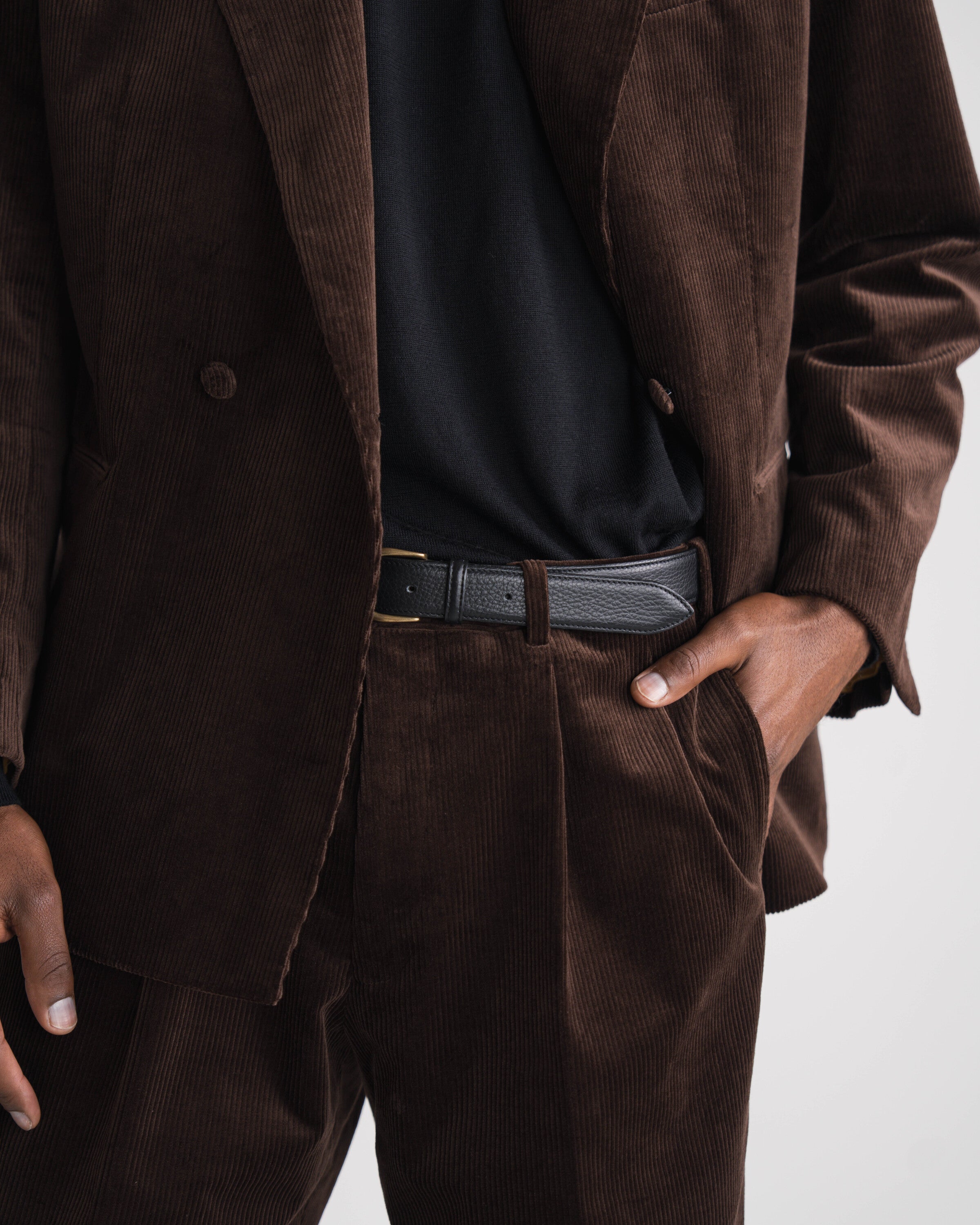 donkerbruin ribfluweel kostuum zittende man met bruine trui