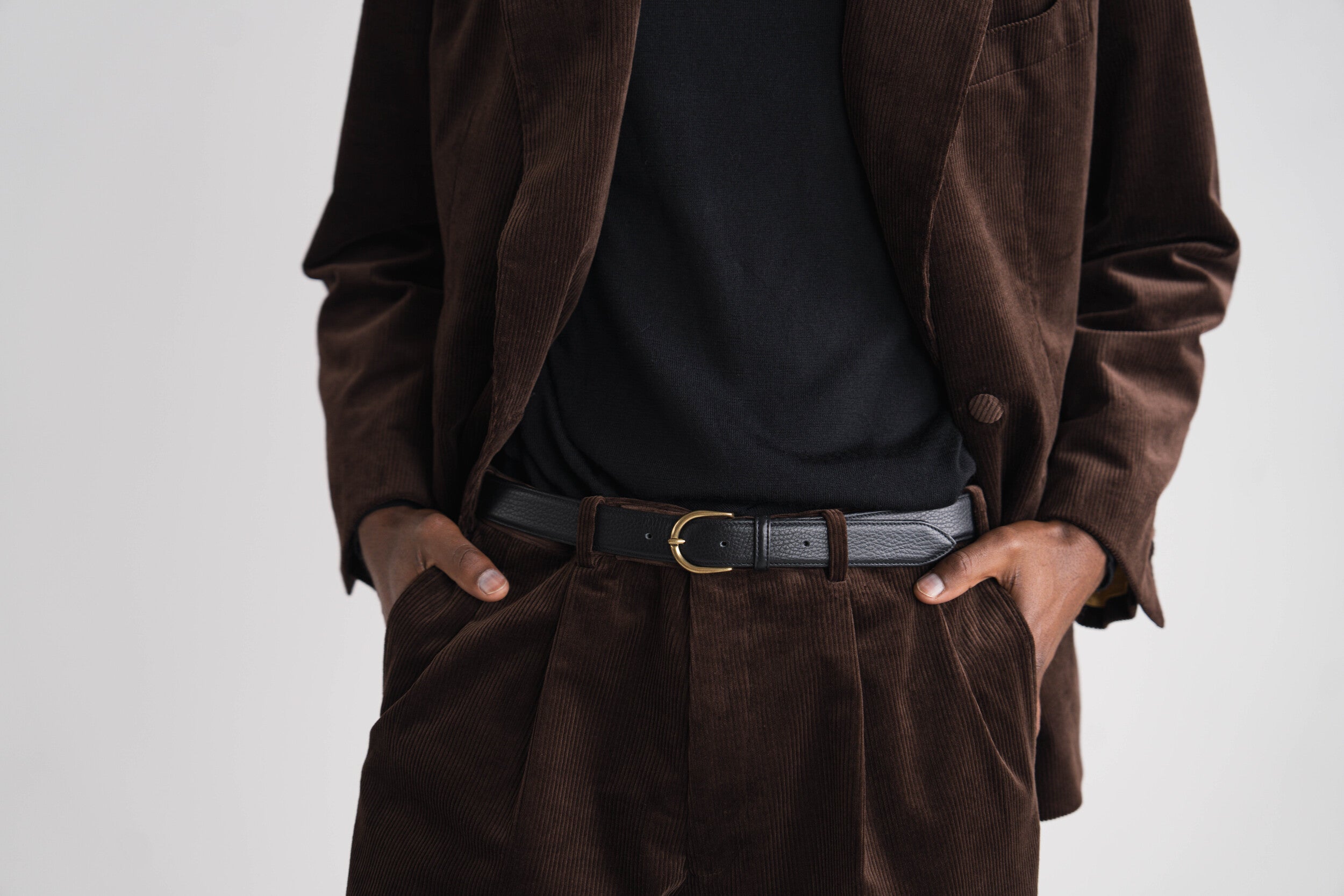 donkerbruin kostuum zittende man met zwarte trui