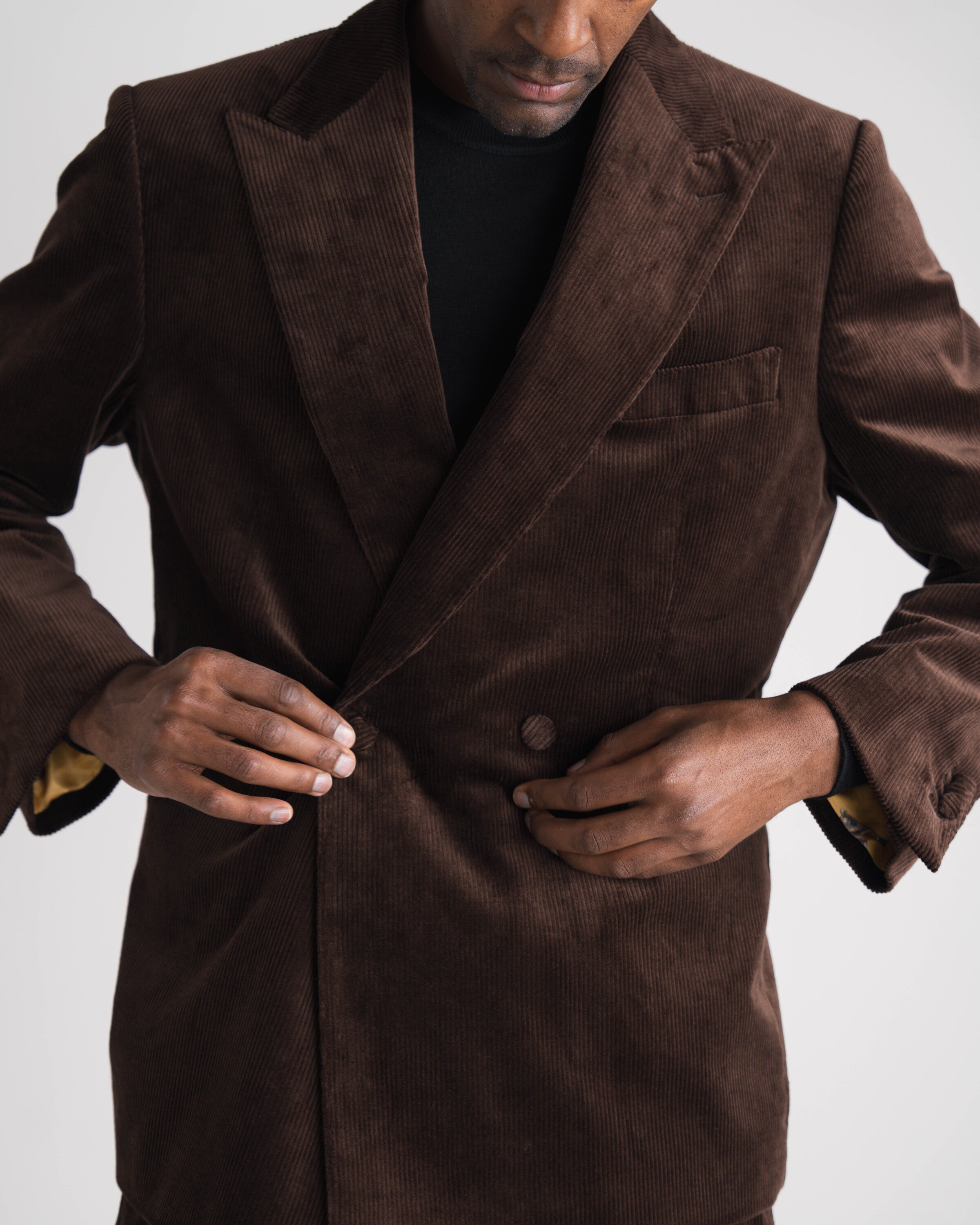 donkerbruin kostuum zittende man met zwarte trui