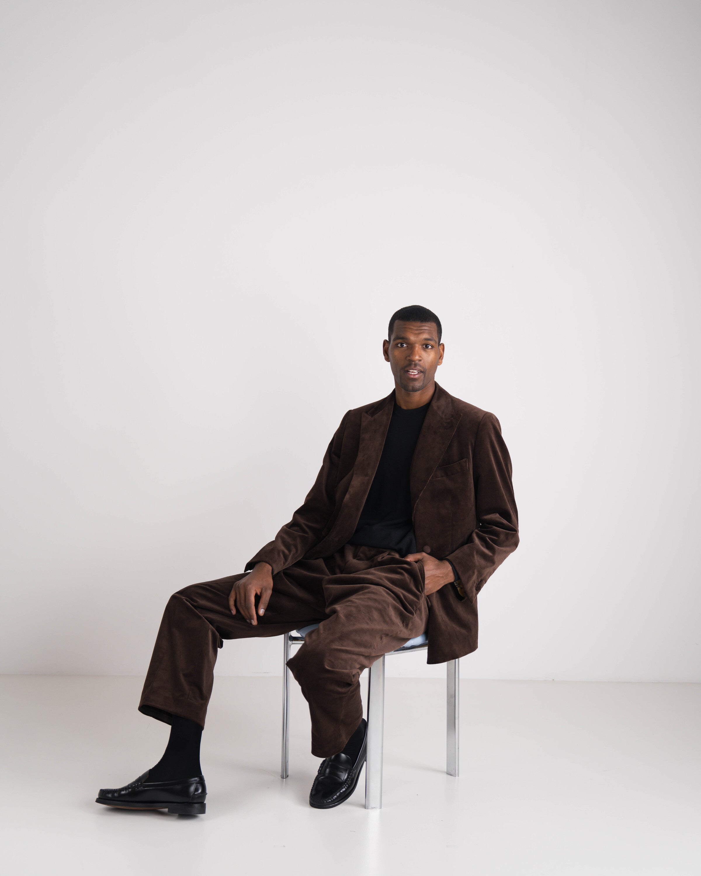 donkerbruin kostuum zittende man met zwarte trui