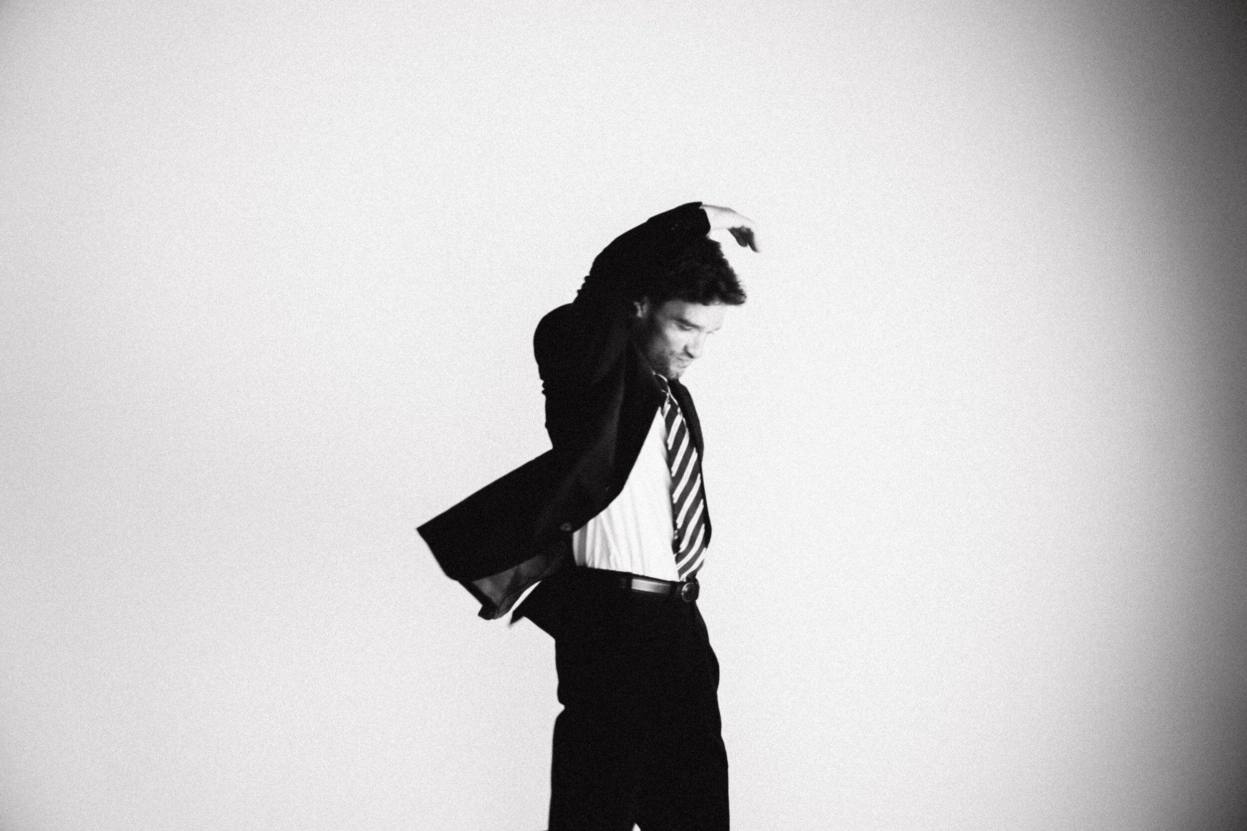 Model die zwaaiend met zijn arm poseert in zijn maatpak van Atelier ACÀN