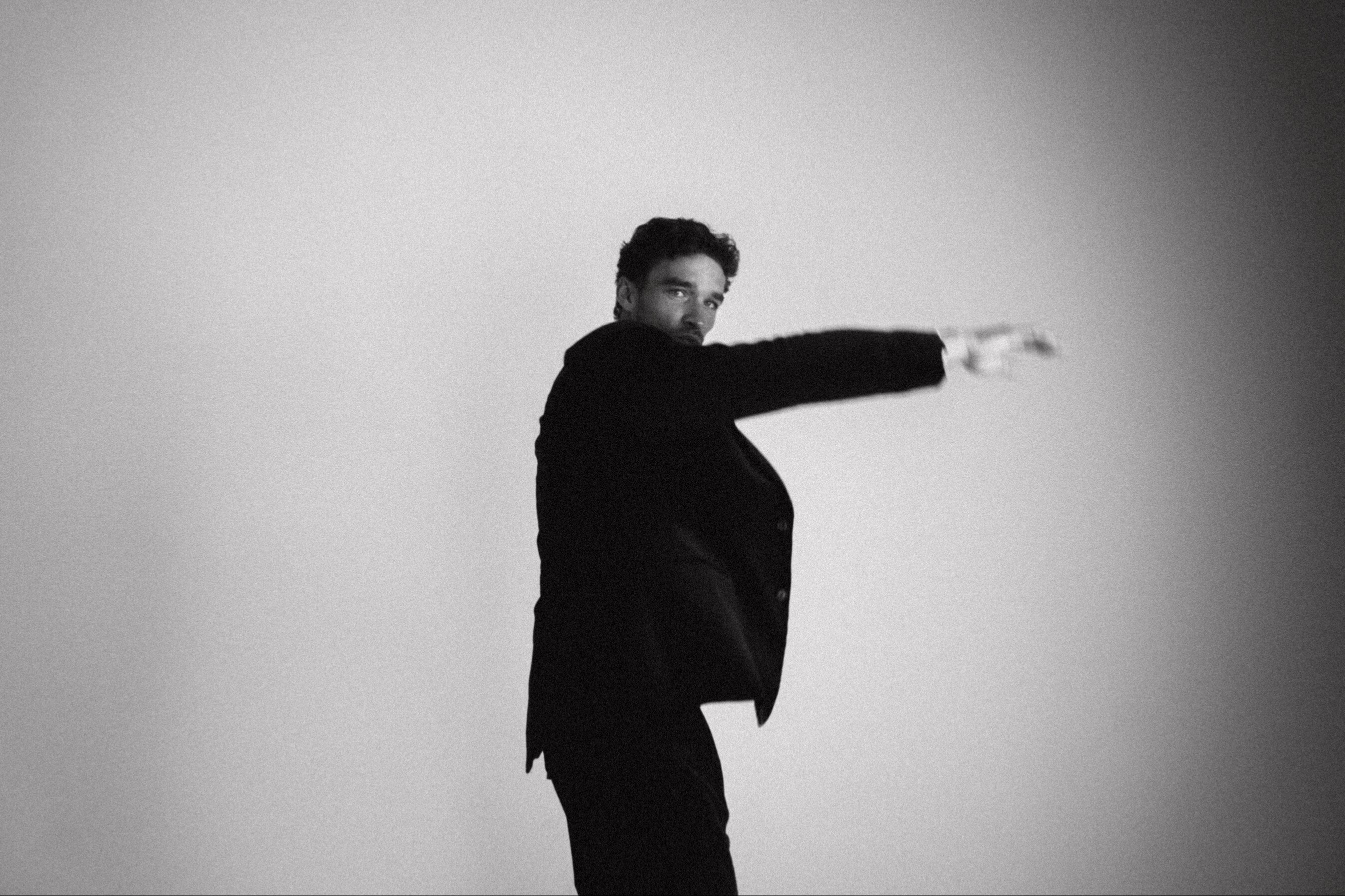 Man in een kostuum die in draaiende beweging poseert. Editorial look