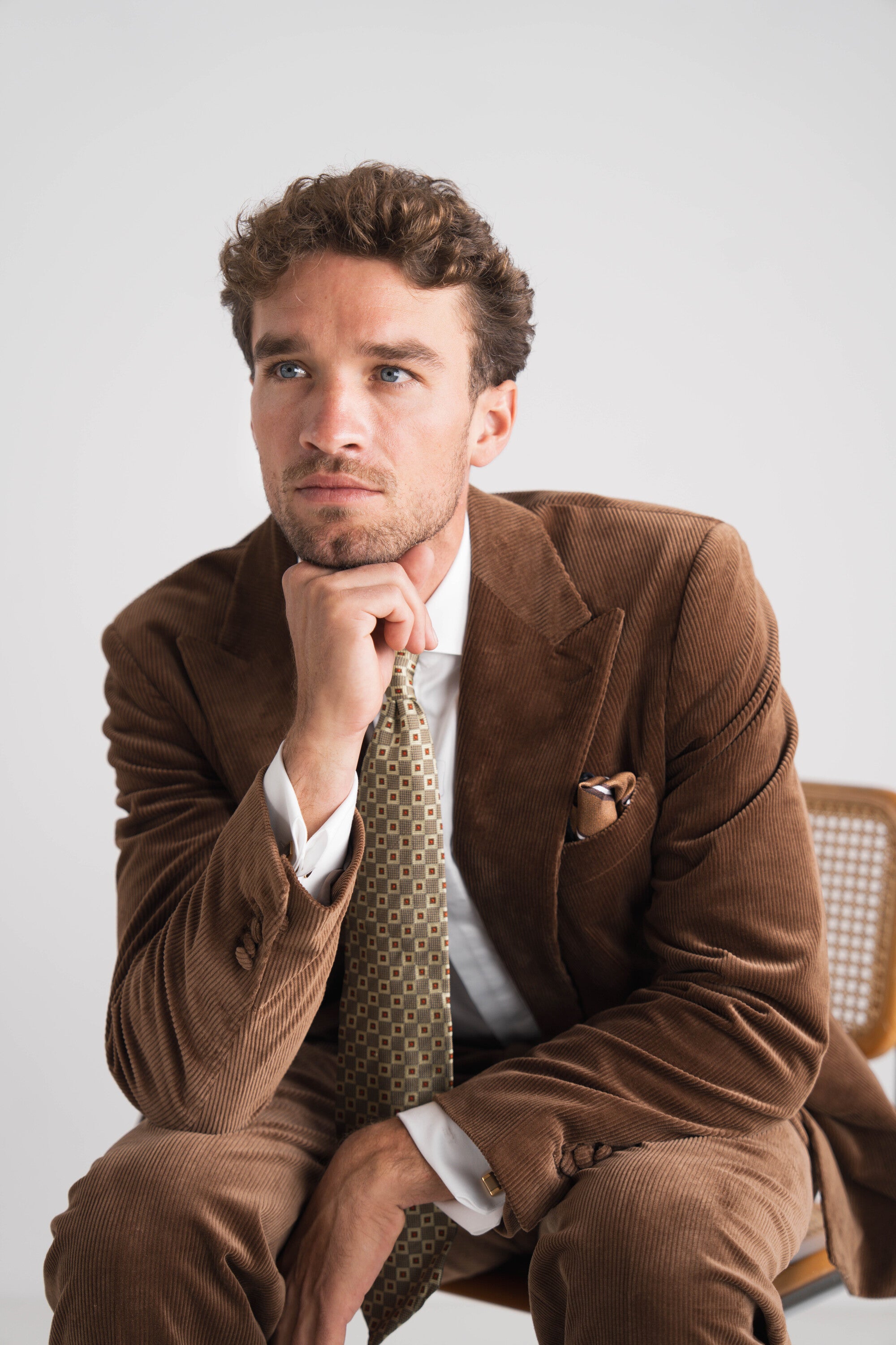 man met donkerbruin pak met wit hemd en groene das