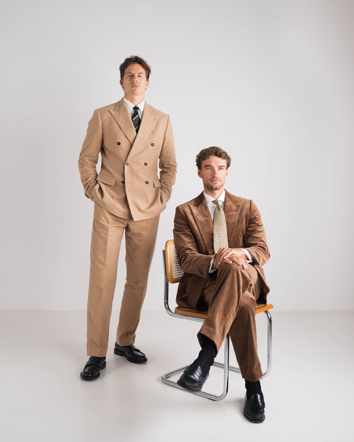 twee mannen in bruin corduroy kostuum en andere in camel double breasted en das 