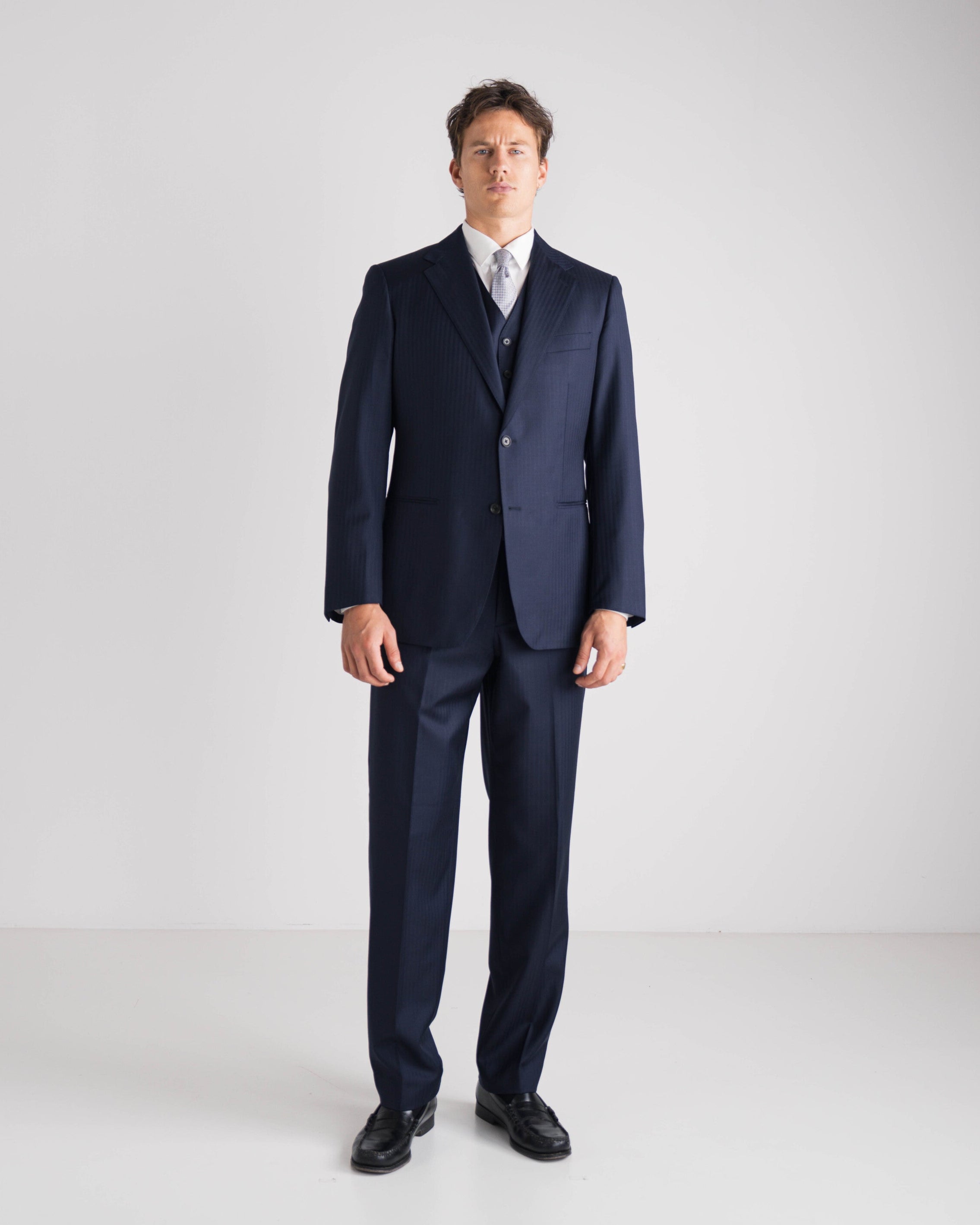 Man wearing a navy three-piece suit on a white background