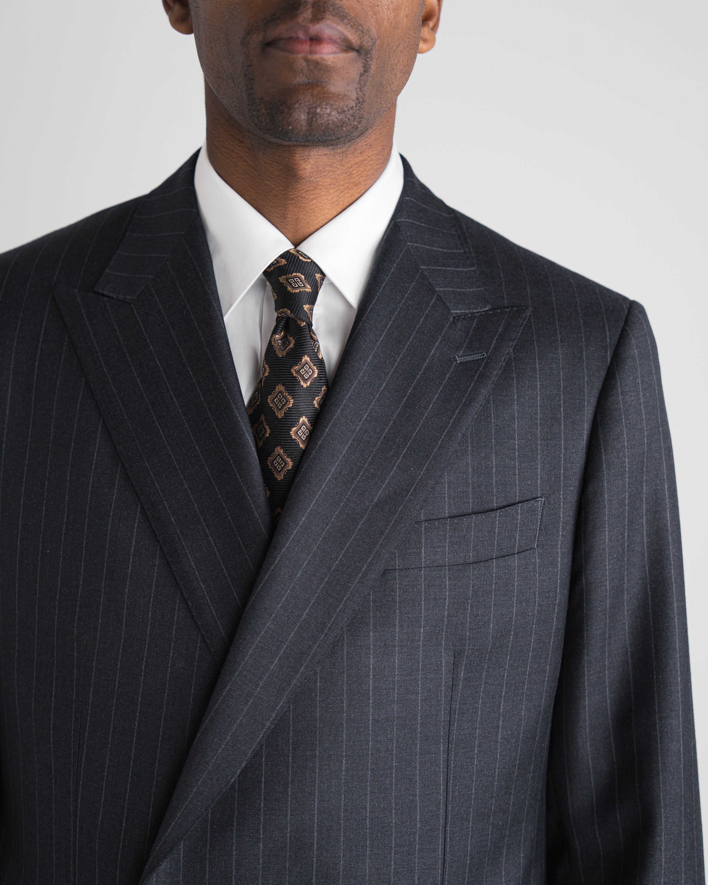 Een man in een donkergrijs pak met strepen, double-breasted met een das van Atelier ACÀN