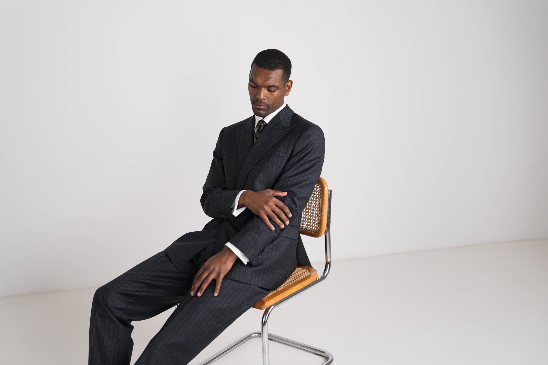 zittende man in donkergrijs pinstripe kostuum met das