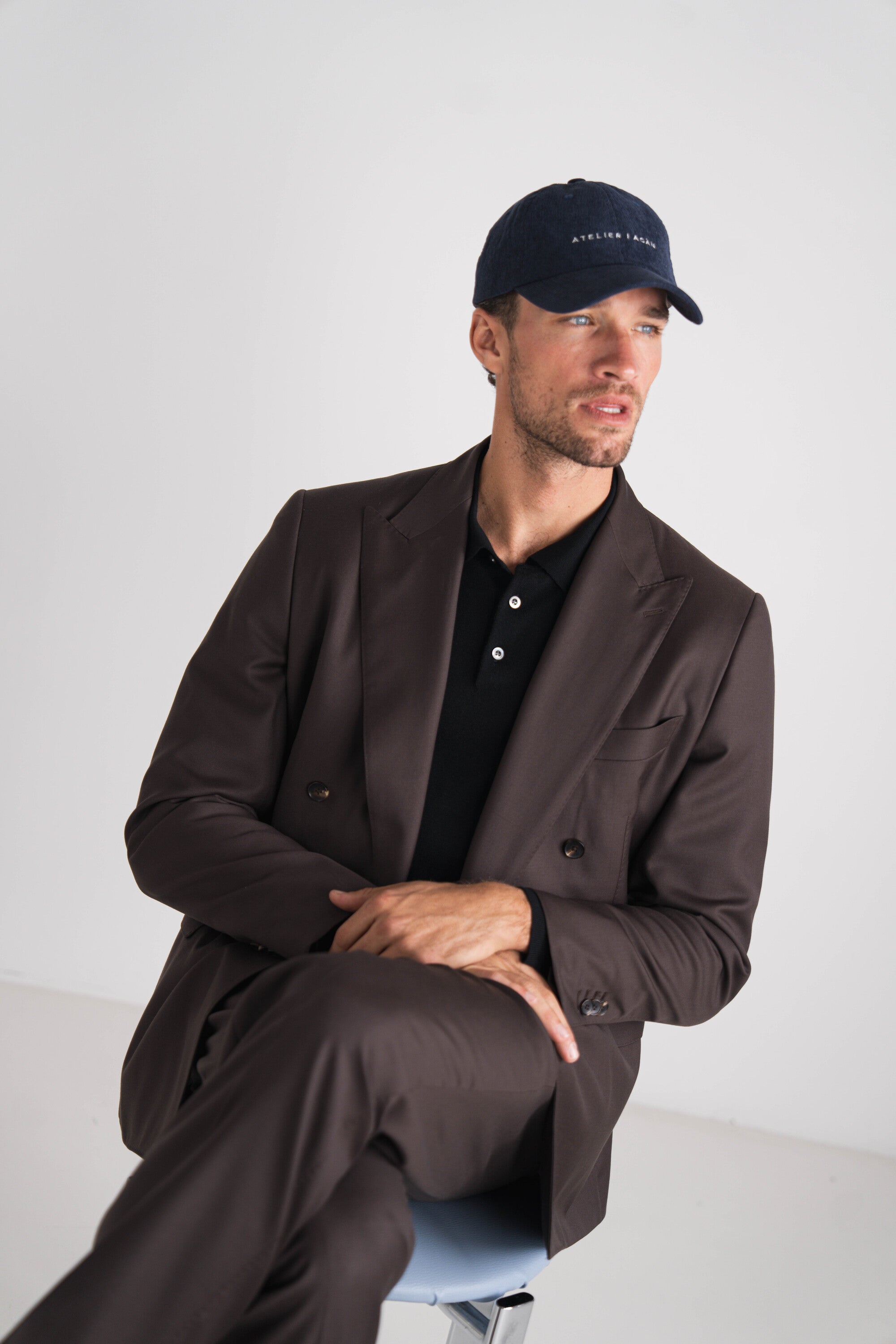 man met bruin kostuum en blauwe pet al zittend