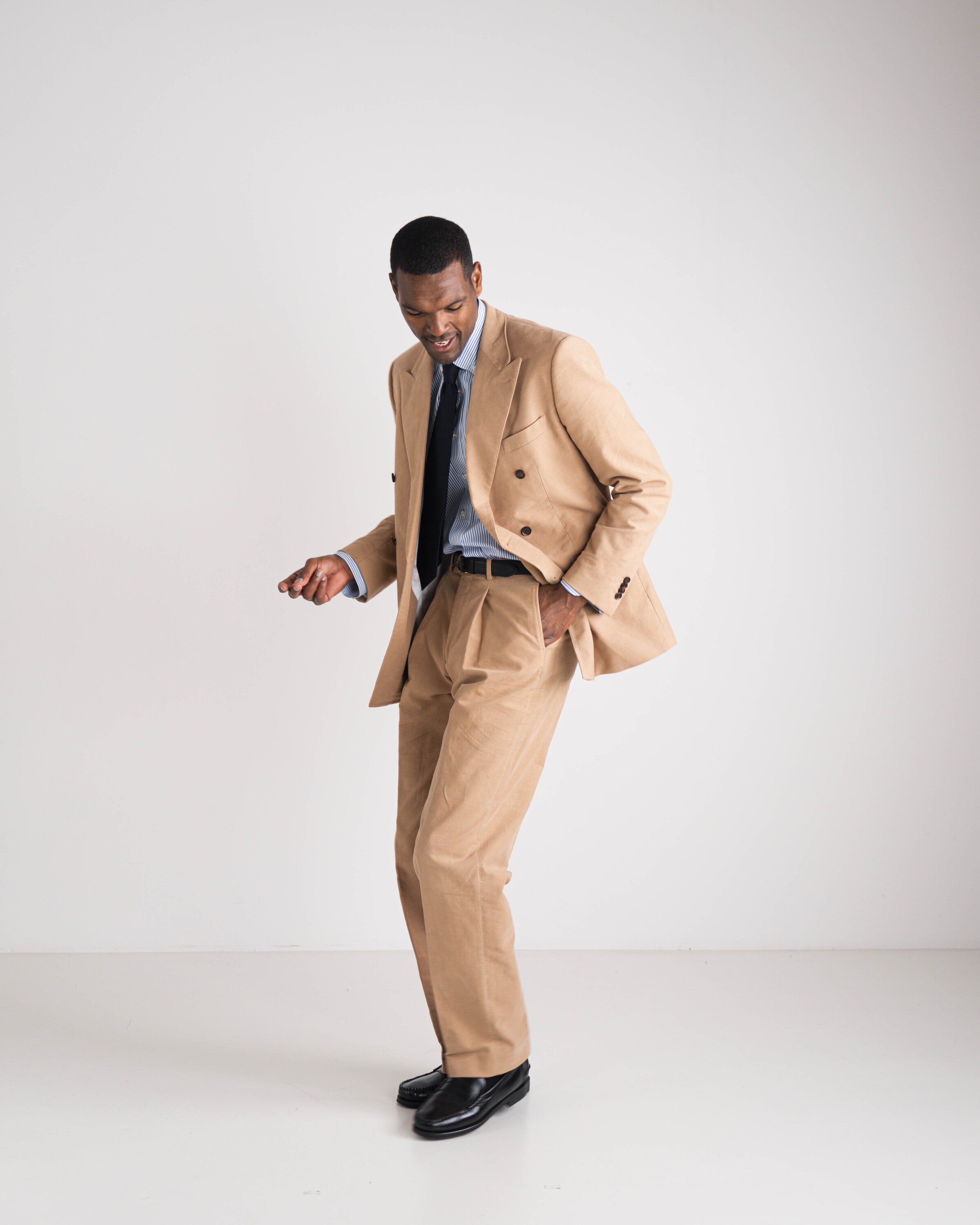 man in camel double breasted kostuum met blauwe das