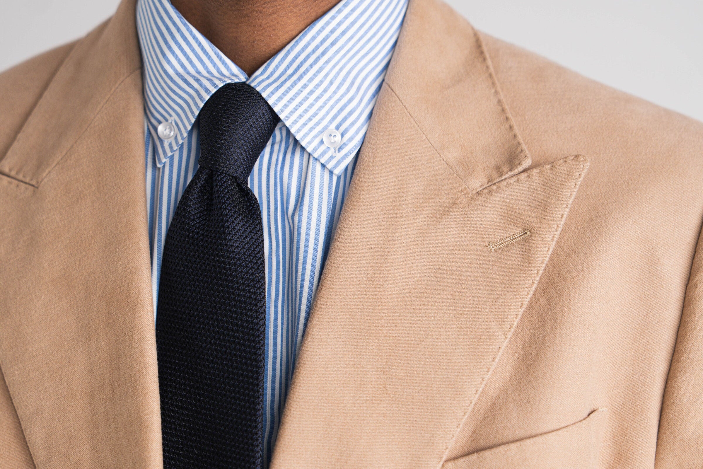 man in camel kostuum met blauw gestreept hemd en blauwe das