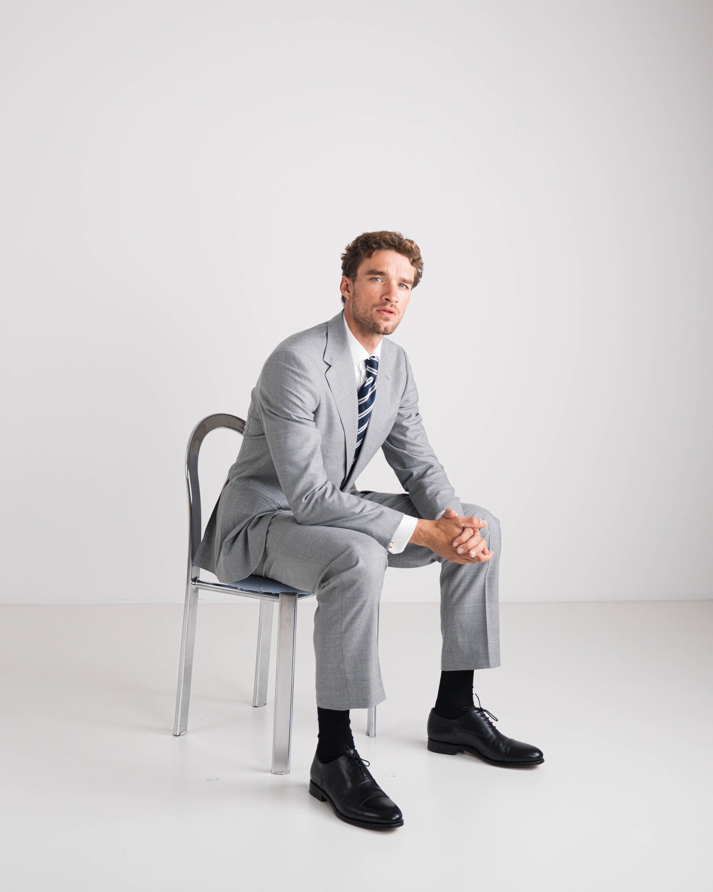 zittende man in grijs pak met blauw gestreepte das