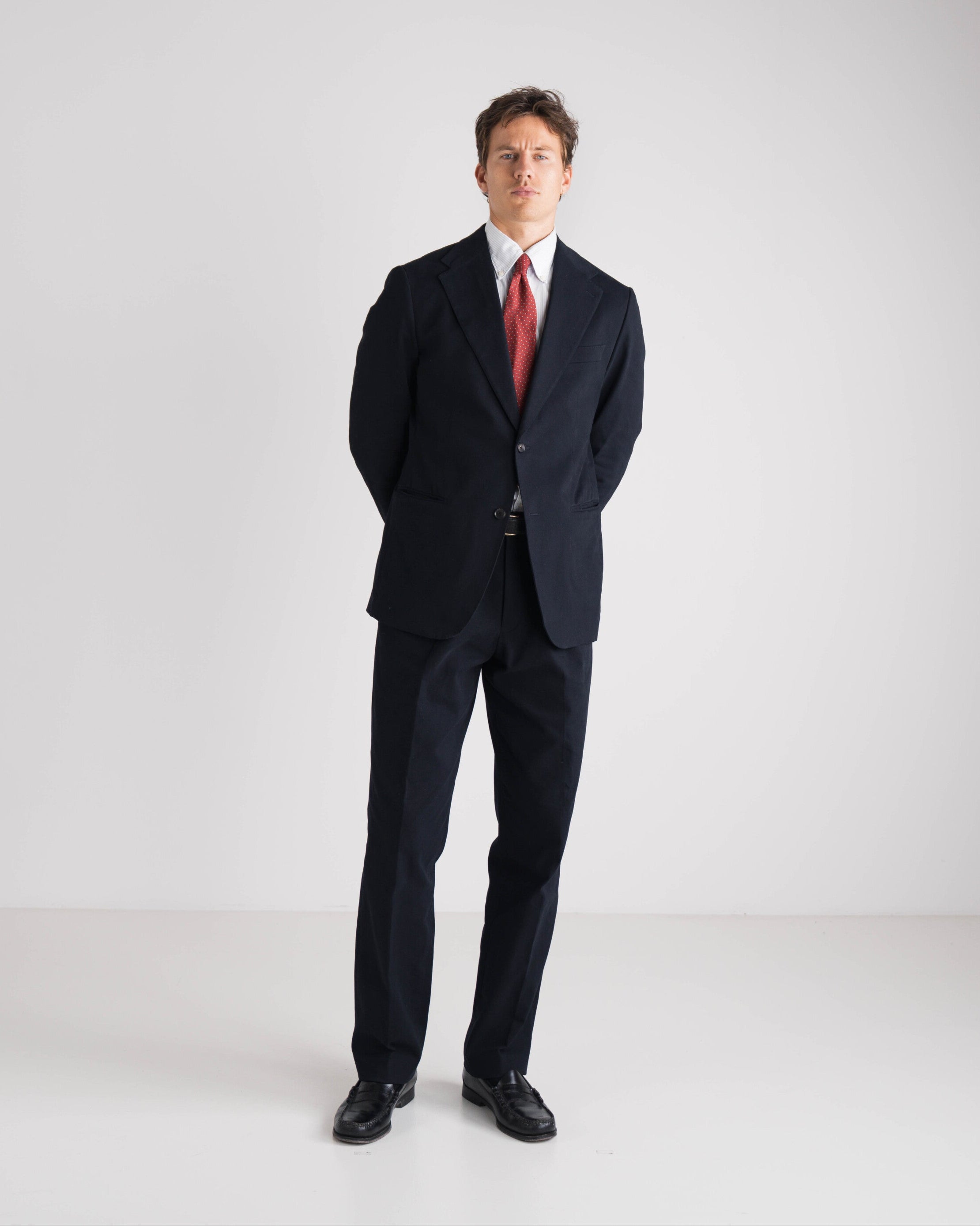Man wearing a black suit with a red tie on a white background