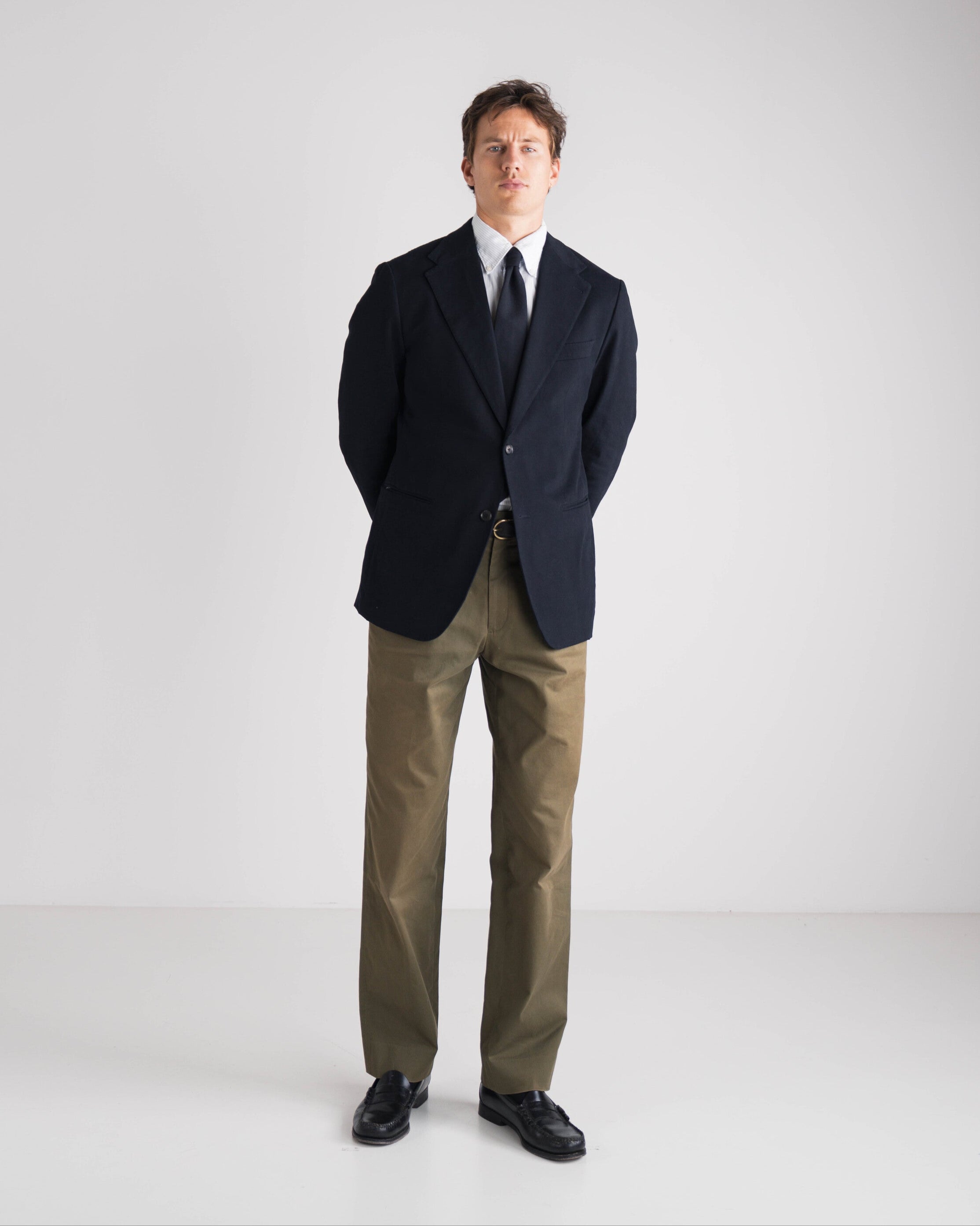 Man in donkerblauwe blazer en groene chino met stropdas op een witte achtergrond