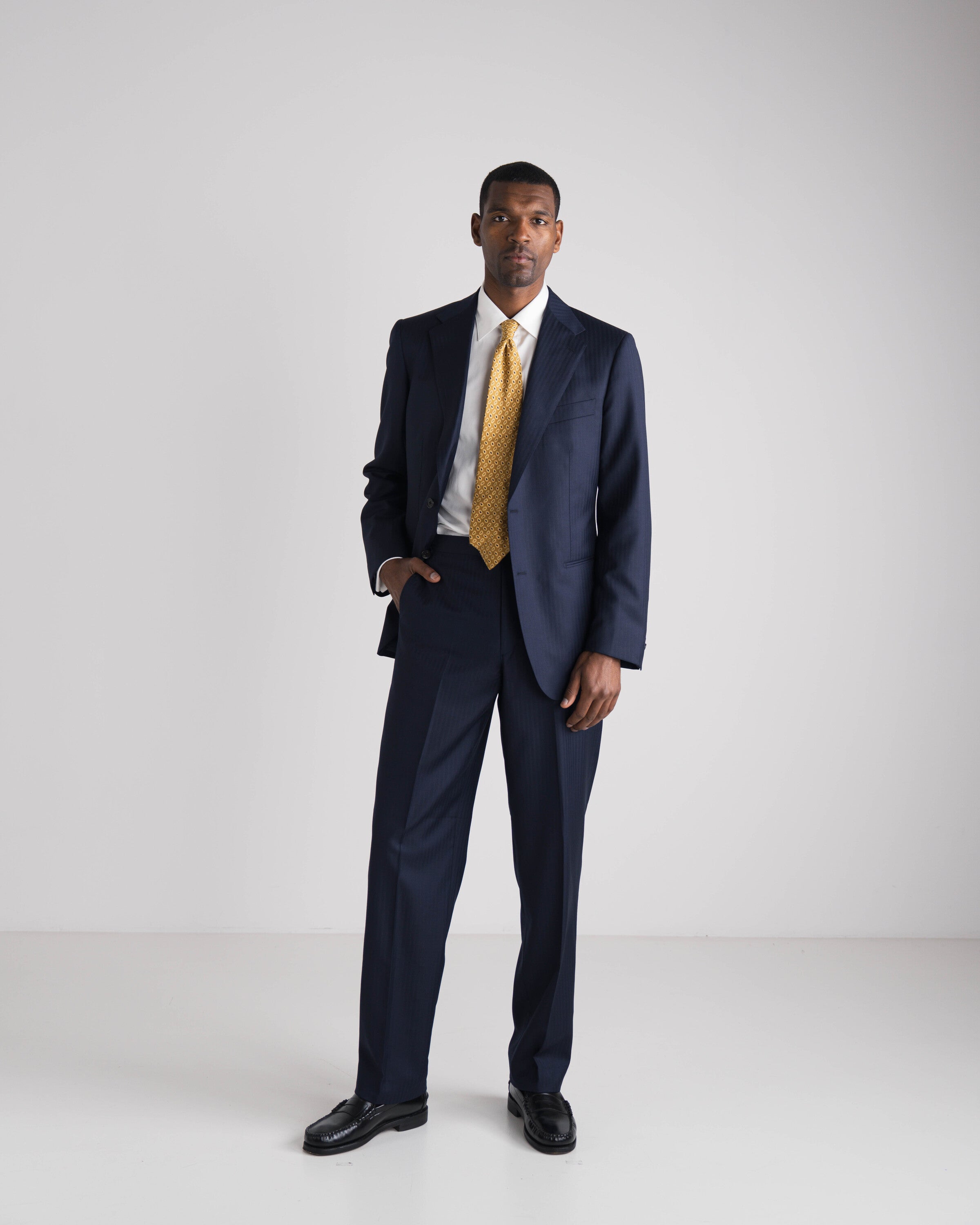 man in blauw kostuum met wit hemd en gele das