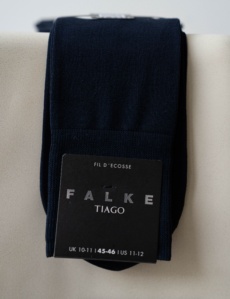 Black Falke Tiago sock on a light gray surface with brand label visible