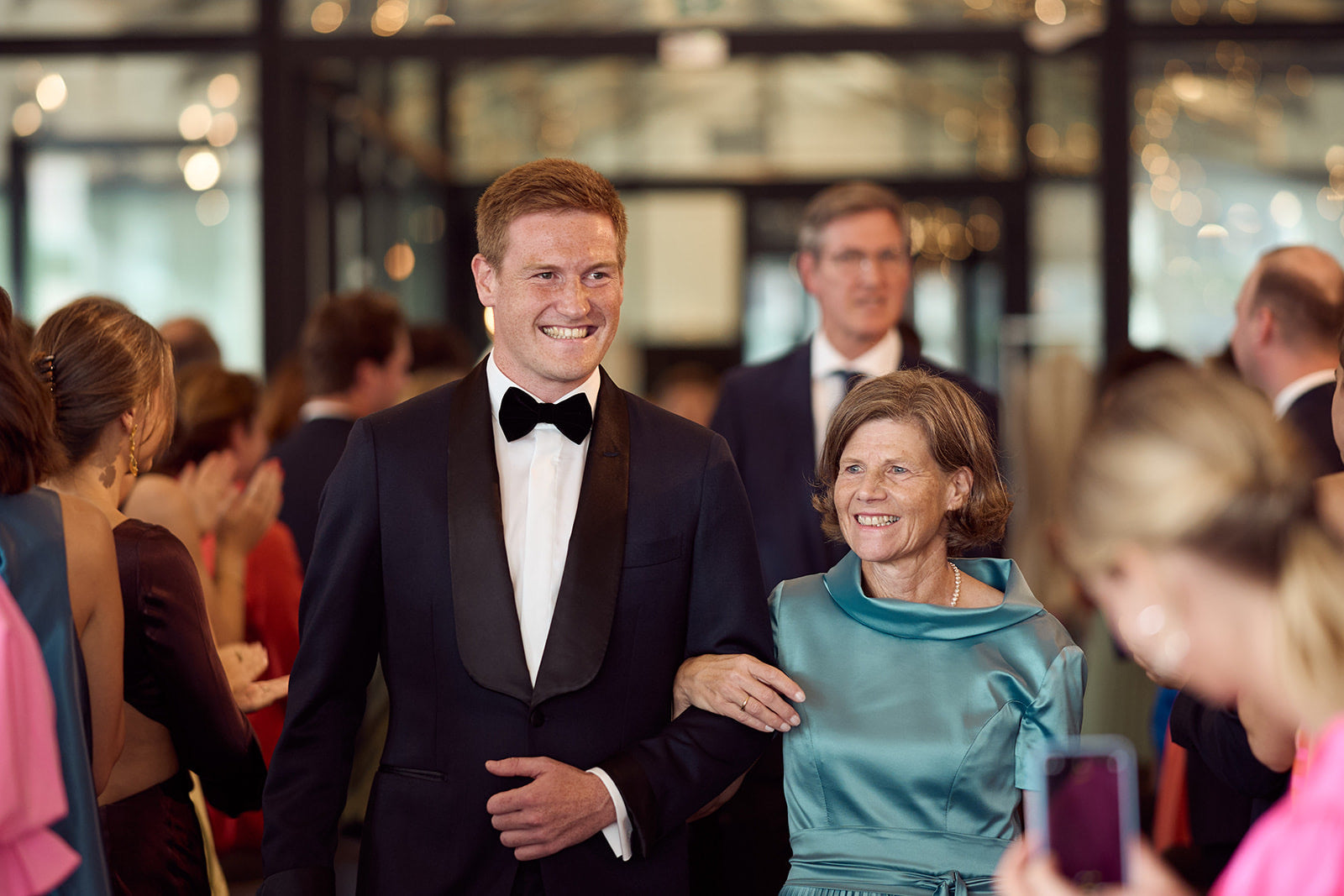Man in a tuxedo standing with a woman in a blue dress at an event.