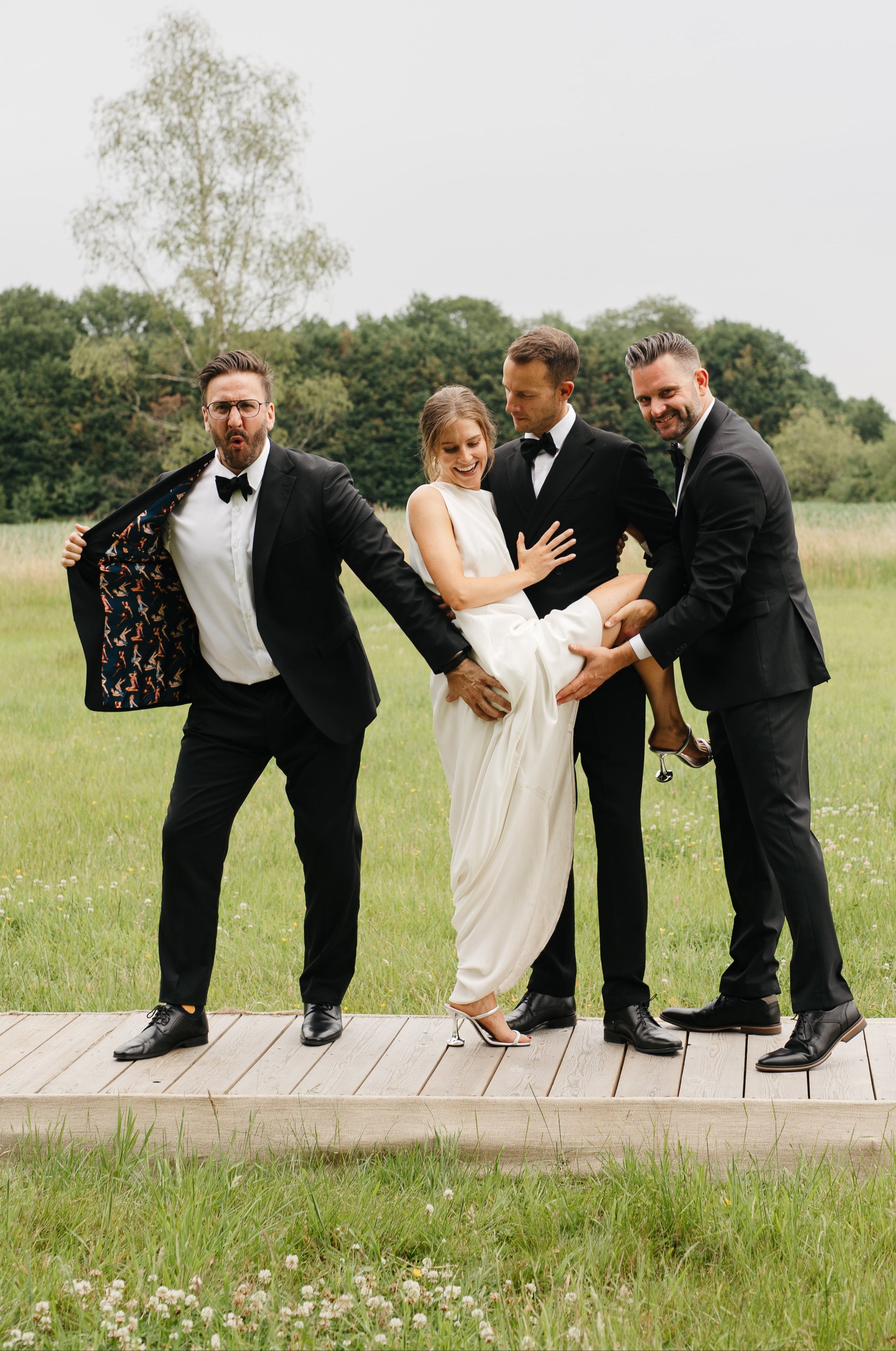de suite poseert met de bruid en bruidegom, ieder met een smoking op maat